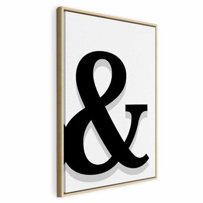 Decorative letter vertical – naturfärgad ram. Ett kraftigt svart &-tecken med en ljusgrå skugga fyller en ren, vit och stående bildyta.