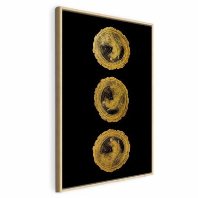 Golden knots vertical – naturfärgad ram. Tre ojämnt målade guldfärgade ringformer ligger i en lodrät rad mot en helt svart bakgrund.