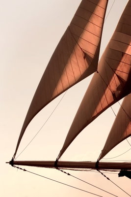 Sea wind vertical – motivvy. Stora brunröda segel och tunna rigglinjer skär diagonalt genom en varmt ljus himmel.