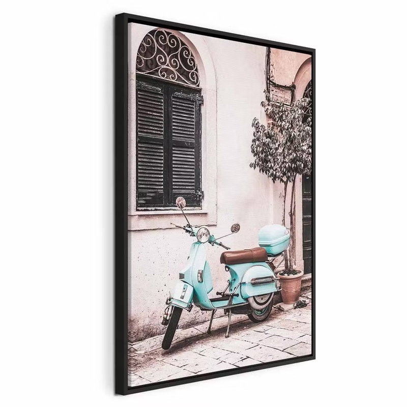 Iconic vespa vertical – svart ram. En turkos skoter står parkerad framför en ljusrosa husvägg med mörka fönsterluckor.