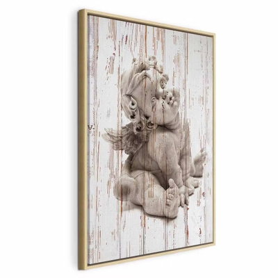 Pensive cupid vertical – naturfärgad ram. En liten ljus figur i eftertänksam ställning återges över en tryckt bakgrund av slitna vita brädor.