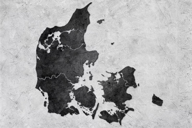 Stone denmark: Danmarks mörka silhuett ligger mot en ljusgrå, stenliknande bakgrund med mjuka färgskiftningar.
