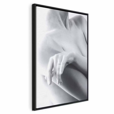 Feminine delicacy vertical – svart ram. En ljus hand vilar mot en naken axel i ett mjukt beskuret svartvitt fotografi.