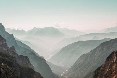Mountain horizon wide – motivvy. Mjuka lager av grågröna berg leder mot en disig, nästan vit horisont under en blek himmel.