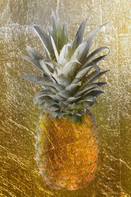 Forbidden fruit vertical – motivvy. En ensam gul ananas med grågröna blad står framför en tät, guldfärgad struktur.
