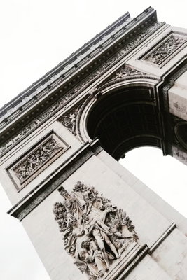 Triumphal arch vertical – motivvy. En utsmyckad triumfbåge ses nedifrån i svart och vitt, med tydliga linjer och ljus himmel.