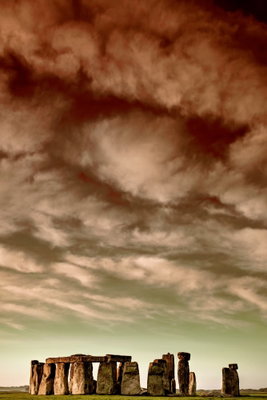 Clouds over stonehenge – motivvy. En rad stora, mörka stenar står längs en låg horisont under en vid bruntonad molnhimmel.