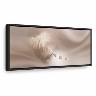Delicate feather – svart ram. En liten ljus fjäder och några runda detaljer ligger över böljande, varmt beige skuggor i ett smalt panorama.