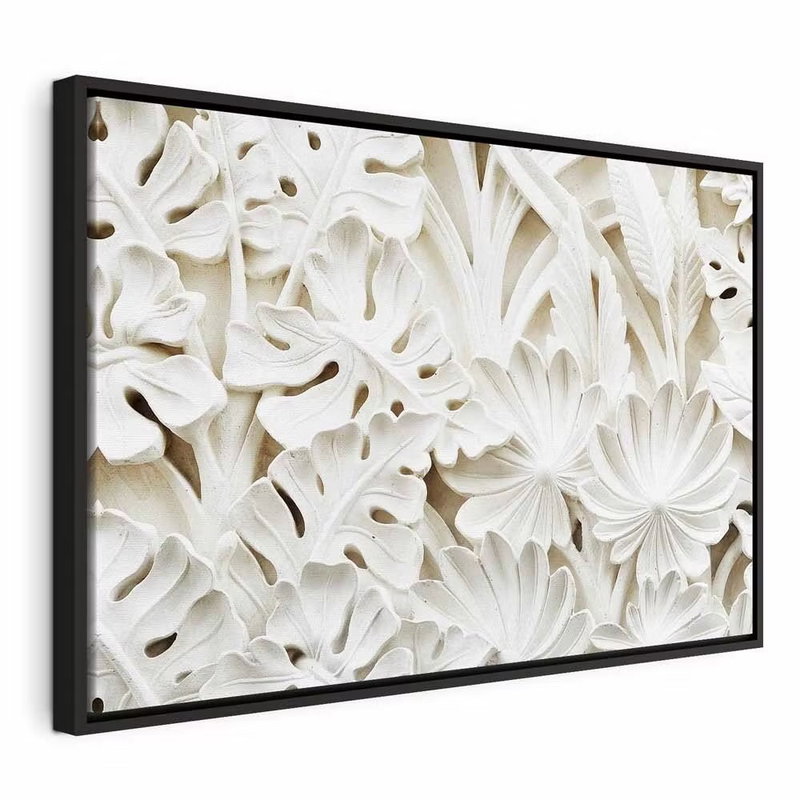 Ceramic leaves wide – svart ram. Täta vita blad- och blomformer med tydliga skuggor bildar ett tryckt mönster med skenbar relief.