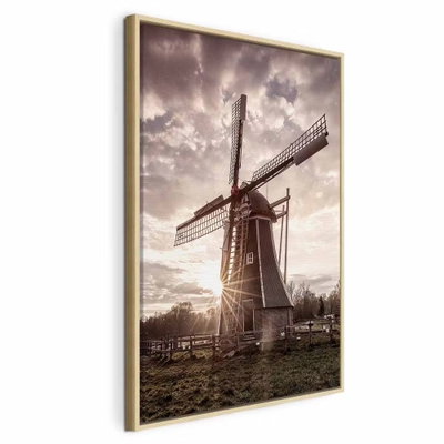Wind of memories vertical – naturfärgad ram. En gammal väderkvarn står under dramatiska moln med lågt solljus bakom byggnaden.