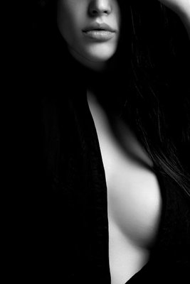 Sensual elegance vertical – motivvy. Ljusa delar av ett ansikte och en överkropp framträder ur en nästan svart bakgrund.