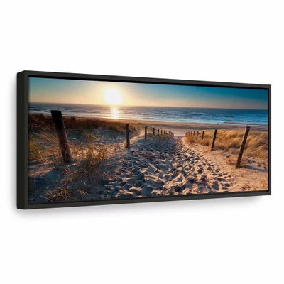 Sunset path – svart ram. En stig mellan låga staket leder över sanddyner mot havet och ett varmt ljus vid horisonten.