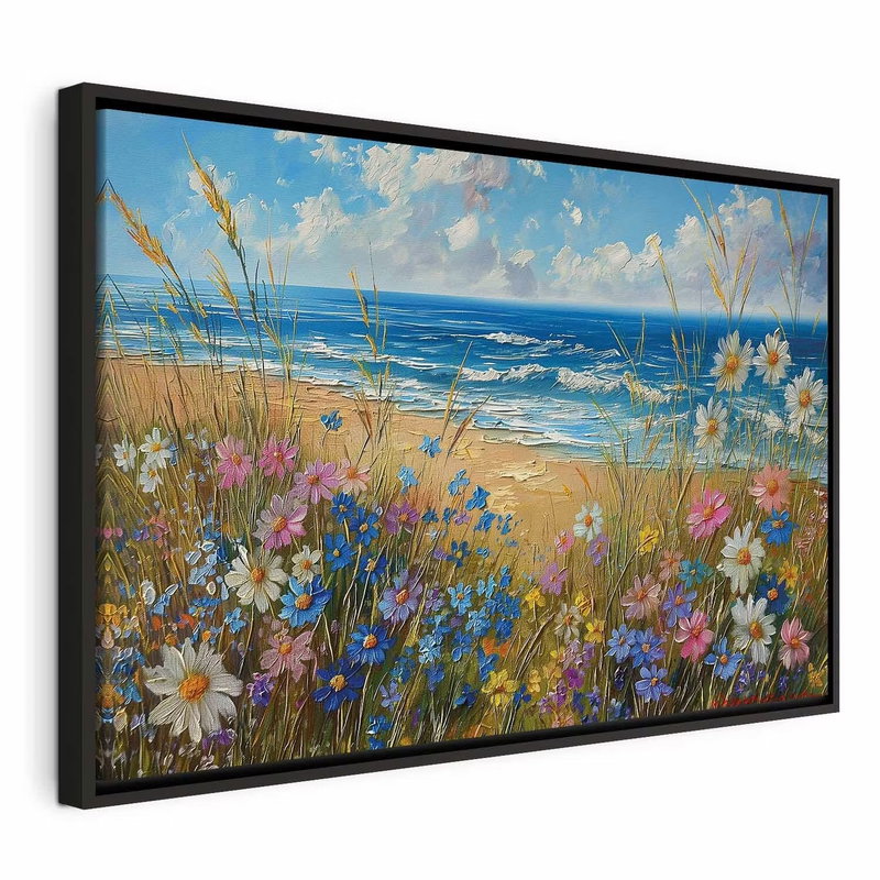 Seascape wildflowers and a – svart ram. Vita, rosa och blå ängsblommor växer framför en sandstrand och ett blått hav under ljus molnhimmel.