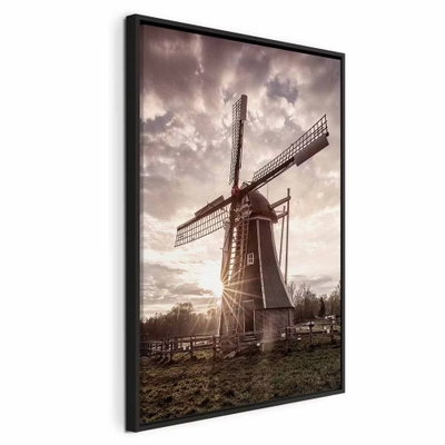 Wind of memories vertical – svart ram. En gammal väderkvarn står under dramatiska moln med lågt solljus bakom byggnaden.