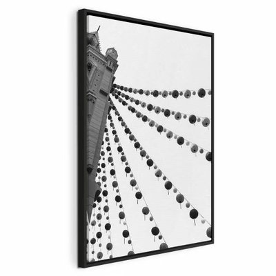 Joyful festival vertical – svart ram. Rader av runda dekorationer sträcker sig mellan byggnader i en svartvit bild sedd underifrån.
