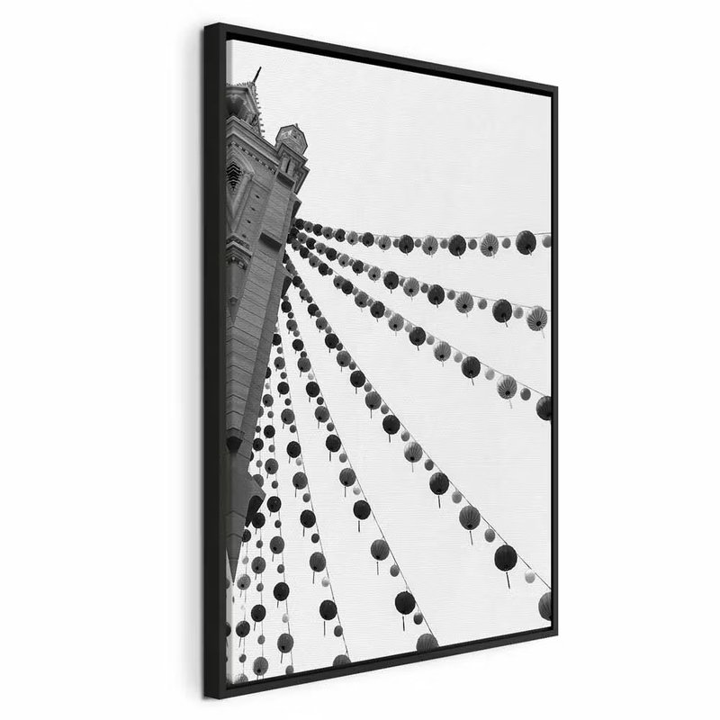Joyful festival vertical – svart ram. Rader av runda dekorationer sträcker sig mellan byggnader i en svartvit bild sedd underifrån.