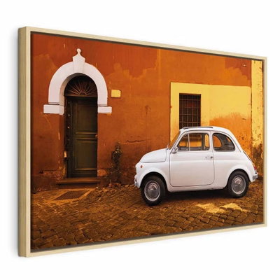 Italian street wide – naturfärgad ram. En liten vit bil står på kullersten framför en orange husvägg med mörk dörr och vita detaljer.