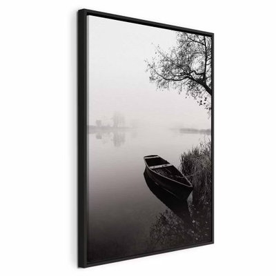 Haven under tree vertical – svart ram. En mörk träbåt ligger vid en strand under ett utsträckt träd i ett dimmigt svartvitt landskap.