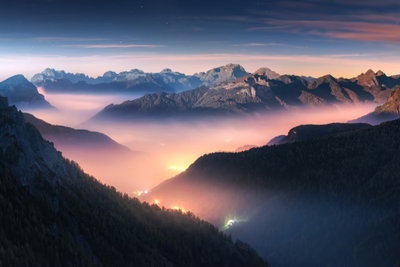 Mountain breath wide first – motivvy. Mörka berg omsluter en lång dal fylld av rosa och orange dimma under blåtonade avlägsna berg och en ljus kvällshimmel.