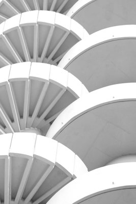 White detail vertical – motivvy. Upprepade vita, böjda arkitekturformer skapar rytm genom ljus och mjuka grå skuggor.