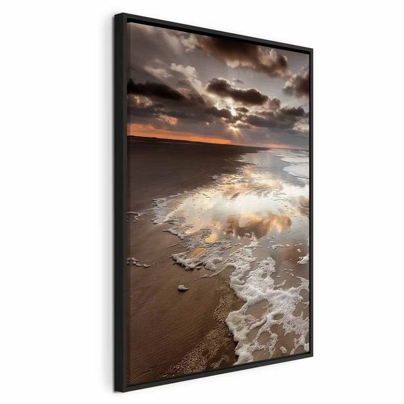 Present distraction vertical – svart ram. Vita vågor rullar in över en sandstrand under en dramatisk molnhimmel med ett smalt varmt ljus vid horisonten.