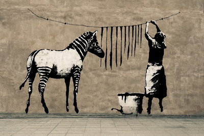 Banksy washing zebra on – motivvy. En zebra står intill en person som hänger mörka ränder på en tvättlina i ett svartvitt väggmotiv.
