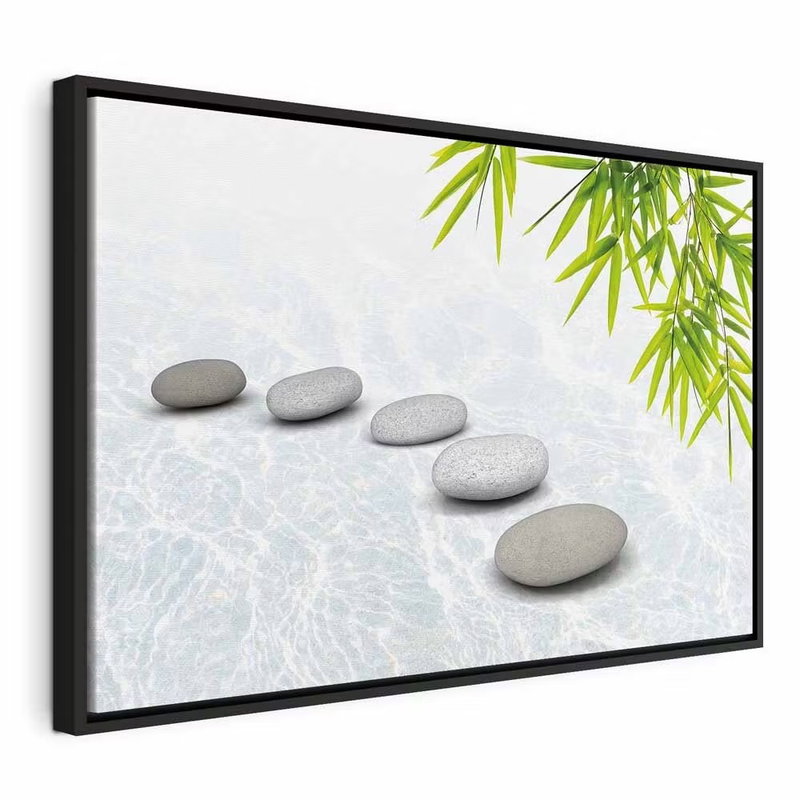 Stone peace wide – svart ram. En rad släta grå stenar ligger på en ljus yta med gröna bambublad i bildens ena hörn.