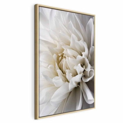 White dahlia – naturfärgad ram. Vita kronblad ligger tätt kring dahlians ljusa mitt. De mjuka skuggorna mellan bladen ger blomman djup mot en återhållen bakgrund i grått och crème.