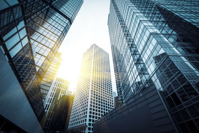 In a big city wide third – motivvy. Solen lyser mellan höga glasbyggnader som speglar blå himmel och omgivande fasader.