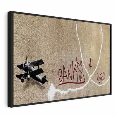 Banksy and s plane red – svart ram. Ett mörkt litet flygplan och långa vita rökspår omger röd handskriftsliknande text på en brungrå botten.