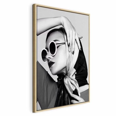 Stylish lady vertical – naturfärgad ram. En kvinna med ljus scarf och runda solglasögon håller en hand över huvudet i ett kontrastrikt svartvitt porträtt.