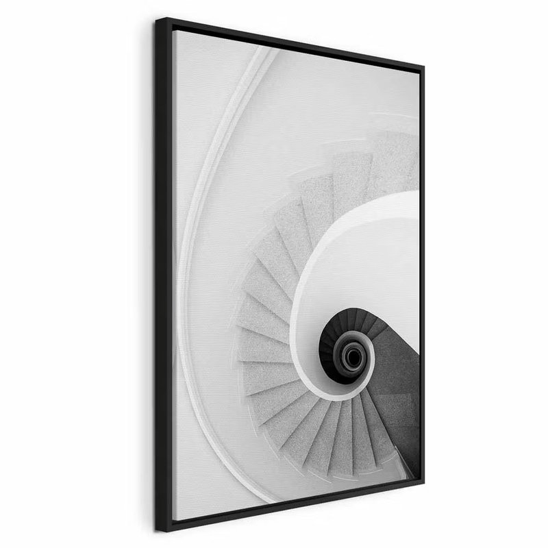 White stairs vertical – svart ram. En vit trappa vrider sig runt en mörk mittpunkt. Räcken och steg ger bilden ett tydligt geometriskt djup.