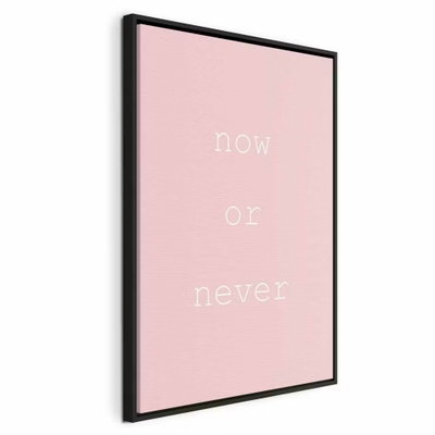 Now or never vertical – svart ram. Orden now or never återges i tunn vit typografi mot en jämnt ljusrosa bakgrund.