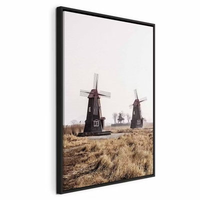 Wooden windmill vertical – svart ram. Flera väderkvarnar står i ett torrt gräslandskap under en blek himmel.