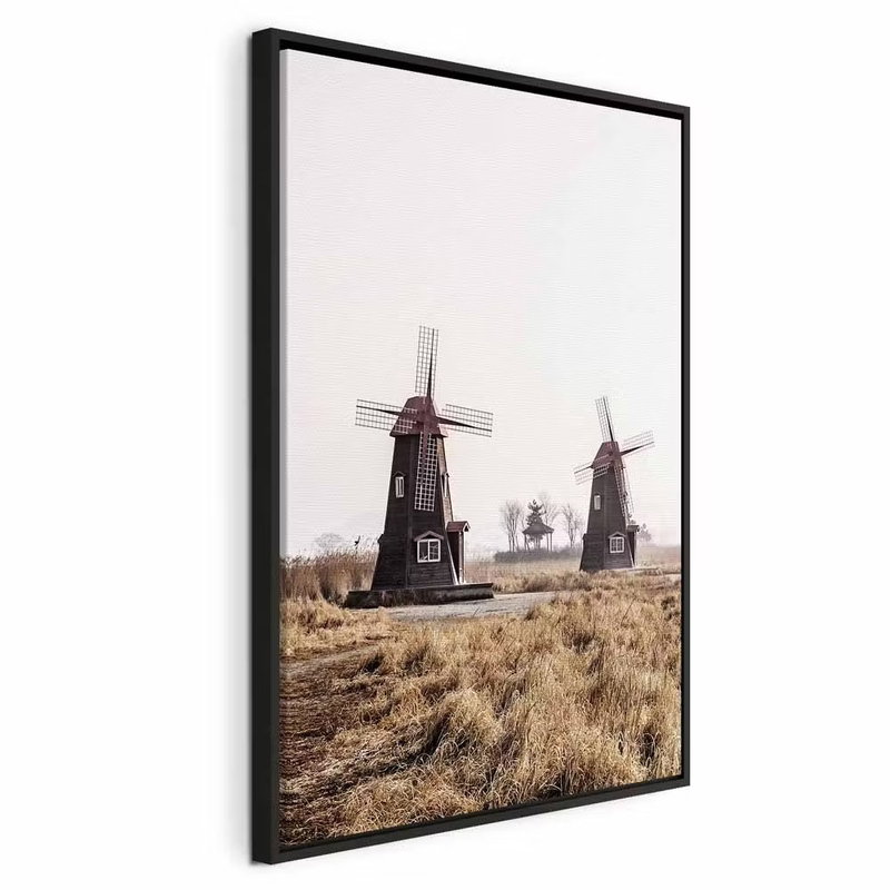 Wooden windmill vertical – svart ram. Flera väderkvarnar står i ett torrt gräslandskap under en blek himmel.