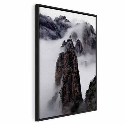 High mountains in mist – svart ram. Smala, mörka bergspelare sticker upp ur en tät vit dimma med mörka berg i bakgrunden.