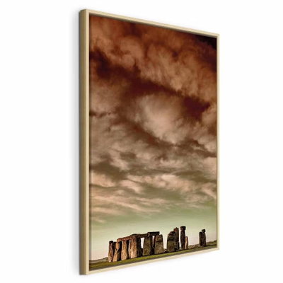 Clouds over stonehenge – naturfärgad ram. En rad stora, mörka stenar står längs en låg horisont under en vid bruntonad molnhimmel.