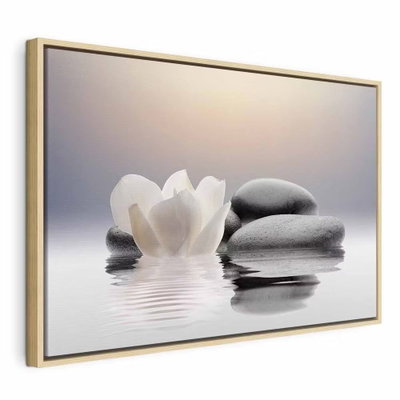 Garden of calm – naturfärgad ram. En vit blomma ligger intill staplade, rundade grå stenar som speglas i en stilla vattenyta.