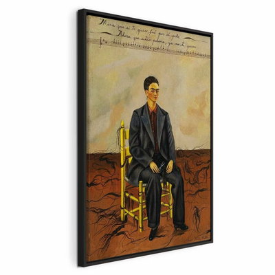 Frida kahlo self portrait – svart ram. En mörkhårig person i kostym sitter på en gul stol på sprucken mark under en ljus vägg med text.