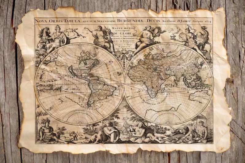 Map of the past: Två cirkelformade kartbilder och dekorativa figurer återges på ett åldrat pappersmotiv framför tryckta träplankor.
