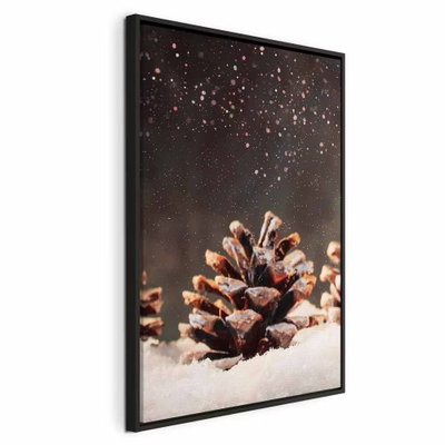 Winter pine cone vertical – svart ram. En brun tallkotte ligger på snö mot en mörk bakgrund med ljusa, glittrande detaljer.