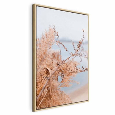 Sophisticated twigs vertical – naturfärgad ram. Tunna, ljust orange kvistar och blad står framför ett mjukt blågrått vattenlandskap.
