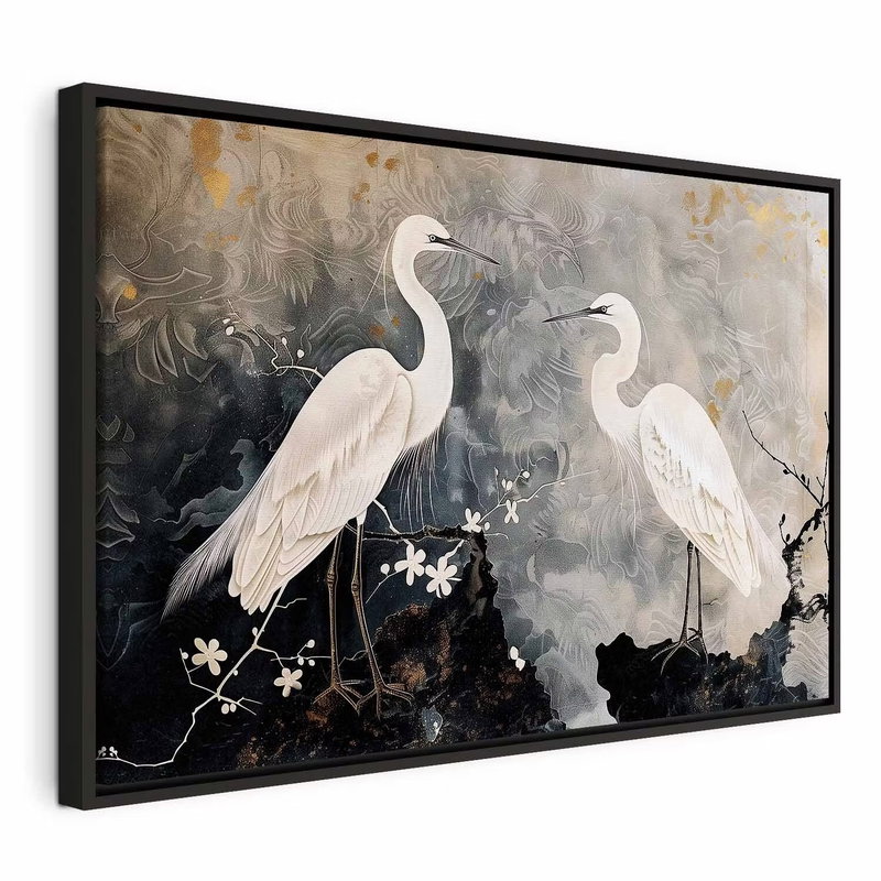 Herons and cherry blossoms – svart ram. Två vita hägrar står på mörka grenar med små vita blommor framför en grå, dekorativ bakgrund.