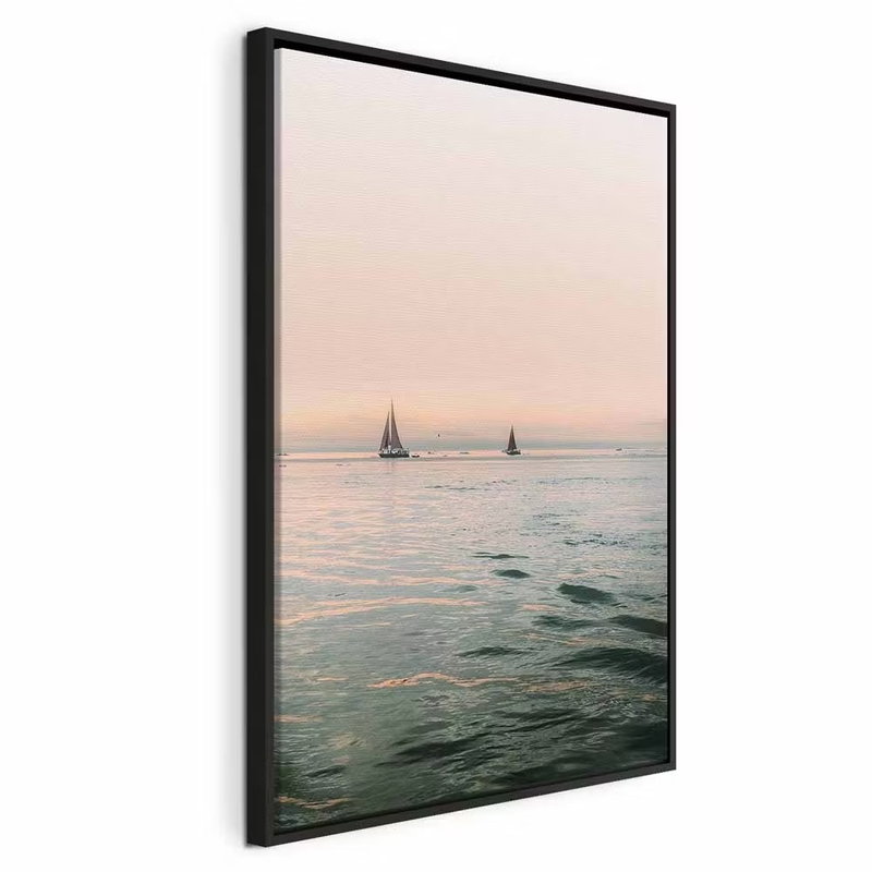 South wind vertical – svart ram. Små segelbåtar syns över lugnt vatten under en stor, ljust rosa himmel.