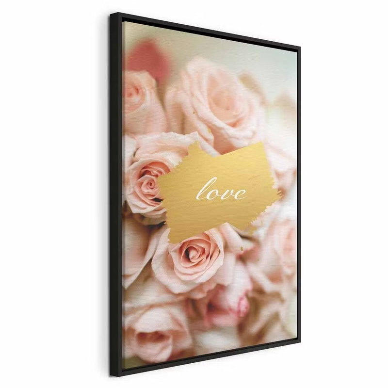 One feeling vertical – svart ram. Mjukt rosa rosor omger ett litet guldfärgat textfält med ordet love.