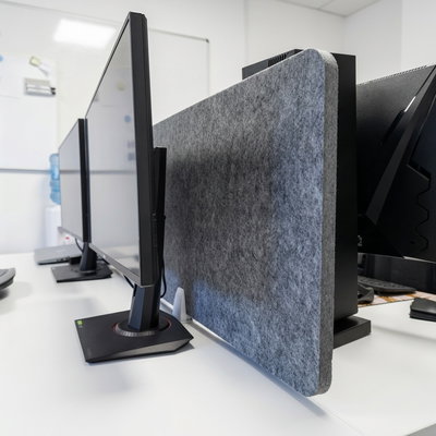 Bulletin Desk Screen: Gray sound-absorbing desk screen mounted behind computer monitors