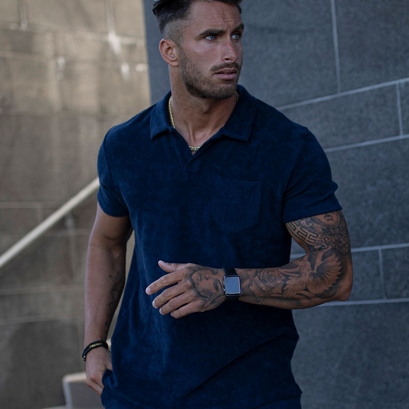 En man med en blå skjorta och shorts på sig.